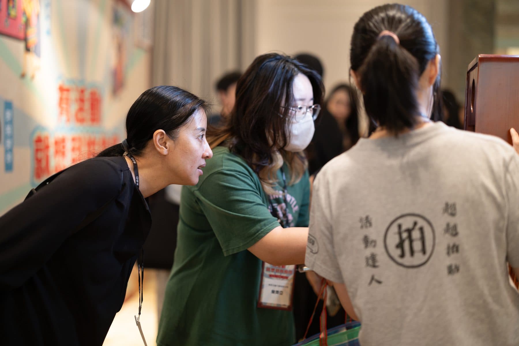 工作人員在影音留聲機攤位旁引導兩位賓客體驗，背景為活動主視覺