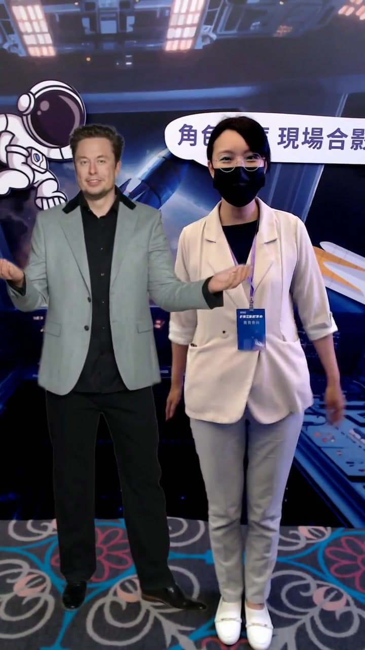 賓客與馬斯克並肩虛擬合影,背景是活動主視覺