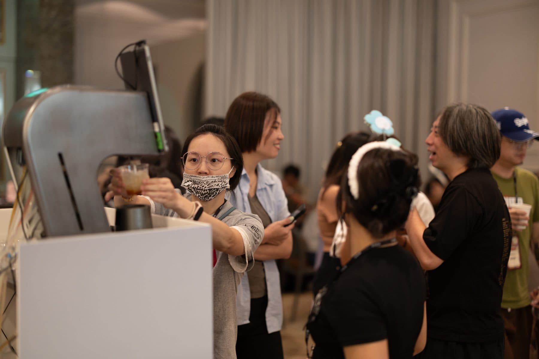 賓客從點點酒智能調酒機取走剛完成的飲品,旁邊還有其他賓客在等候