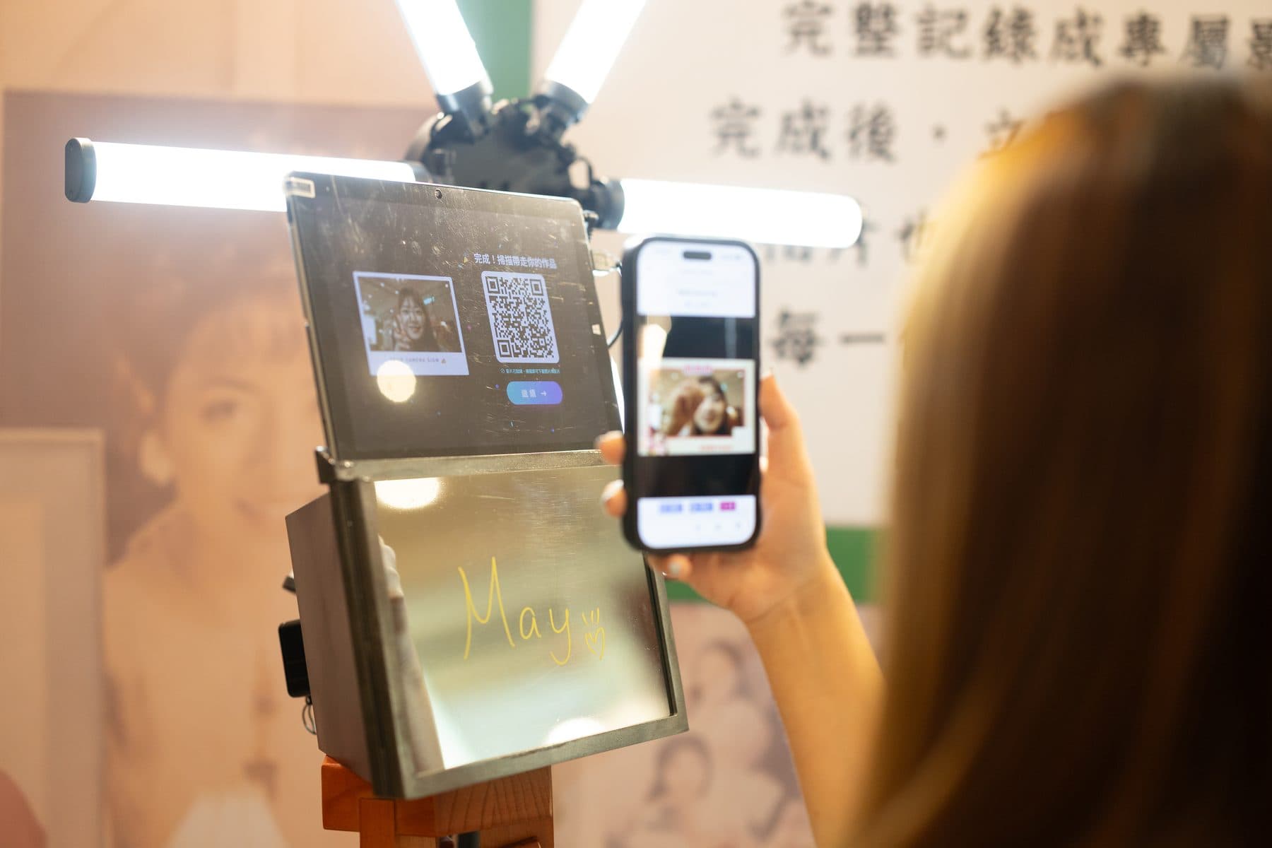 賓客舉起手機掃描機台螢幕上的 QR Code,下方鏡面仍留著剛寫完的手寫簽名