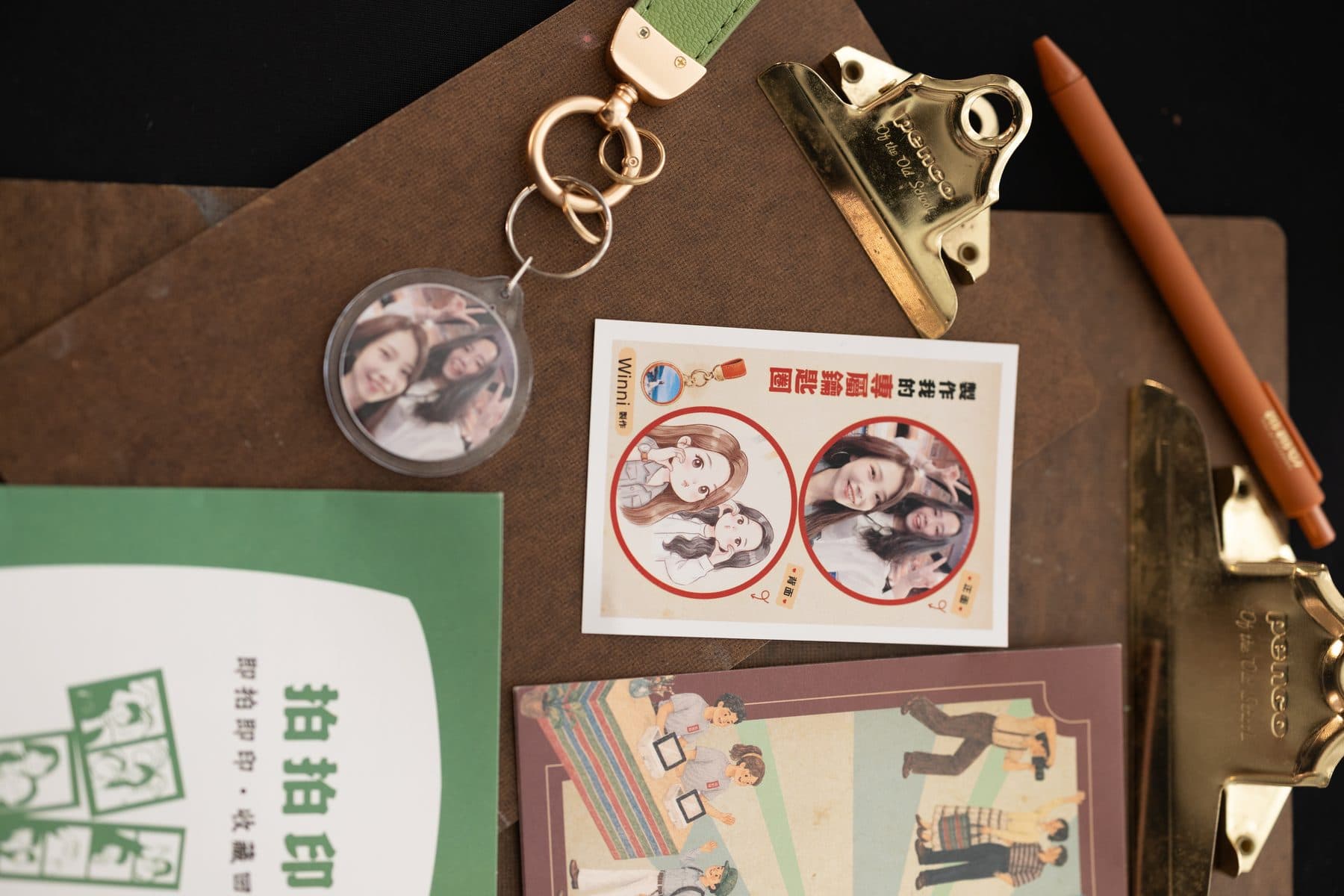 桌面上的壓克力鑰匙圈成品,旁邊有印同一張照片的貼紙與活動 DM